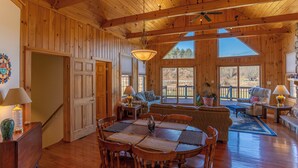 A wooden interior with a dining table, chairs, a sofa, and a ceiling fan. - River House at Meadow Landing (Fleetwood)