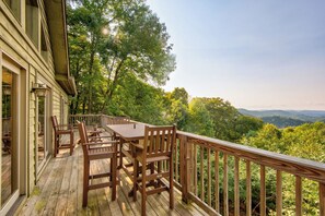 Une terrasse en bois avec une table et des chaises, donnant sur un paysage boisé.