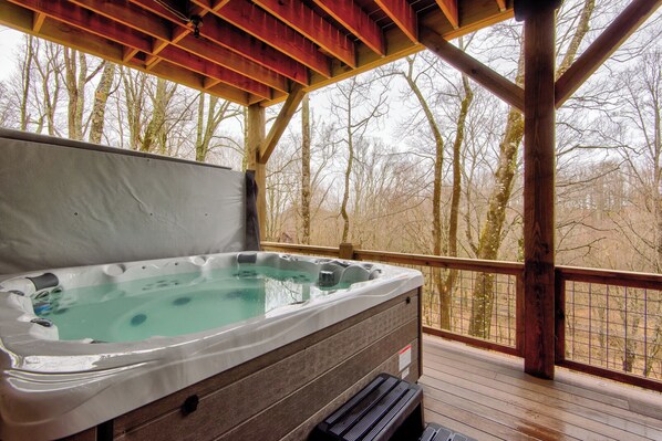 Ein Whirlpool auf einer Holzterrasse mit Blick auf kahle Bäume.