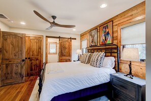 Ein Schlafzimmer mit einem großen Bett, Holzwänden, einem Deckenventilator und Kunstwerken.