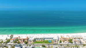 A coastal hotel with a beach view, multiple buildings, and a clear blue ocean.