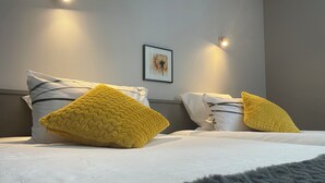 A hotel room with a bed, two pillows, a framed picture on the wall, and two wall-mounted lights. - Castel de Mirambel (Lourdes)