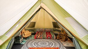 Une tente comprenant un espace de couchage, un tapis à motifs et deux chaises.