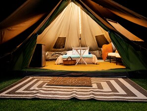 A tent with a bed, a table, and a chair inside. - Creekside Glamping Tent in the Smoky Mountains at Honesuckle Springs (Cosby)