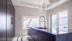 Eine moderne Küche mit einer großen Kochinsel, einem Einbauofen und Meerblick.