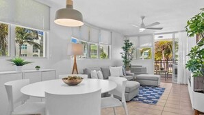 A modern living room with a white dining table, grey sofa, and a ceiling fan. - #15 Chic 3BR, 2BA Apartment at Jobos Beach (Isabela)