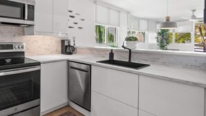 A modern kitchen with white cabinetry, a stainless steel range, a dishwasher, and a large window providing natural light. - #15 Chic 3BR, 2BA Apartment at Jobos Beach (Isabela)