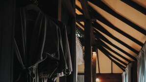 A wooden interior hallway with a bench, a hanging garment, and a wooden door. - Baan Mon Muan  (Mae Rim)
