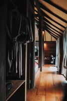 Un pasillo interior de madera con un banco, una prenda colgando y una puerta de madera.