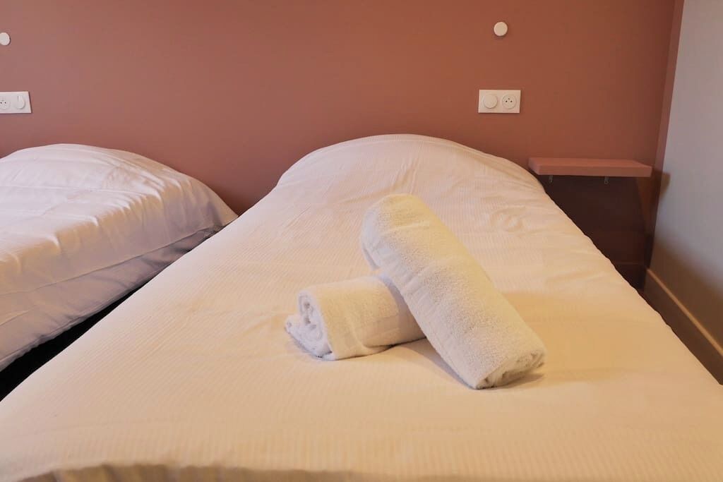 A single bed with a neatly folded white towel on it.