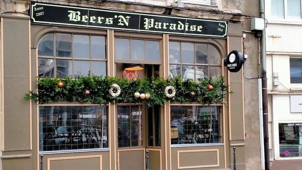 En byggnadsfasad med skylten ”Beers’N Paradise” och en dekorativ krans ovanför ingången.