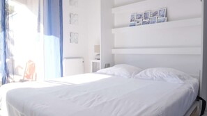 A bedroom with a large bed, a nightstand, a wall-mounted shelf with pictures, and a window with curtains. - Oparadi "Le Nid" Avec sa Terrasse (Wimereux)