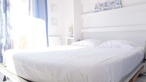 A large bed with white bedding in a bright room with a window and a wall-mounted shelf with pictures. - Oparadi "Le Nid" Avec sa Terrasse (Wimereux)