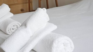 Een opgemaakt bed met opgerolde witte handdoeken.