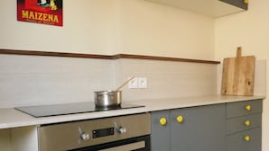 A kitchen with a stove, oven, and a wooden cutting board on the countertop.