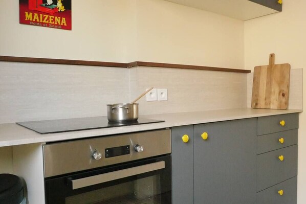 A kitchen with a stove, oven, and a wooden cutting board on the counter.