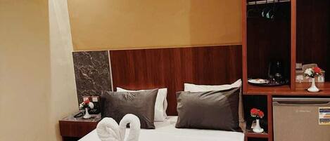 A hotel room with a bed, a nightstand, a minibar, and a wardrobe.