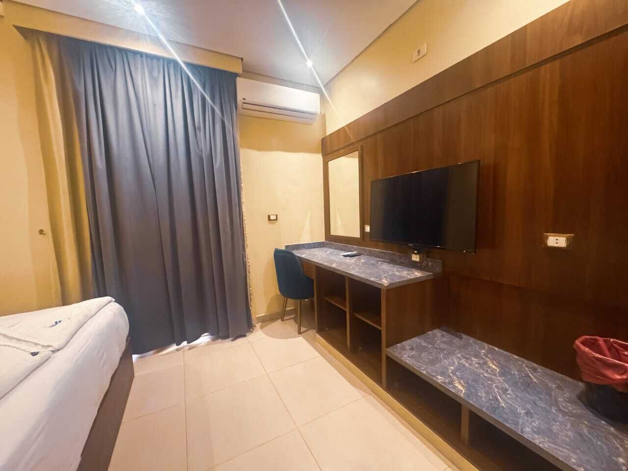 Une chambre d’hôtel avec un lit, un bureau, une chaise, une télévision et un petit banc.