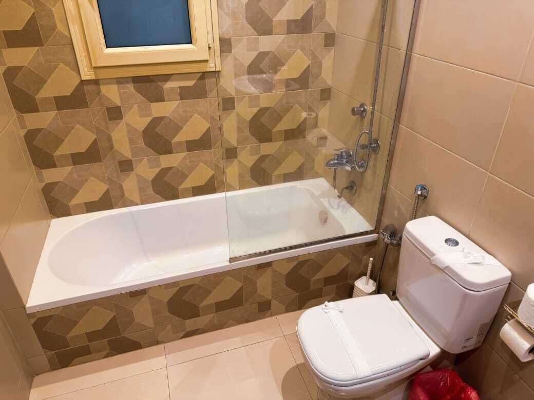 A bathroom with a bathtub, toilet, and shower area.