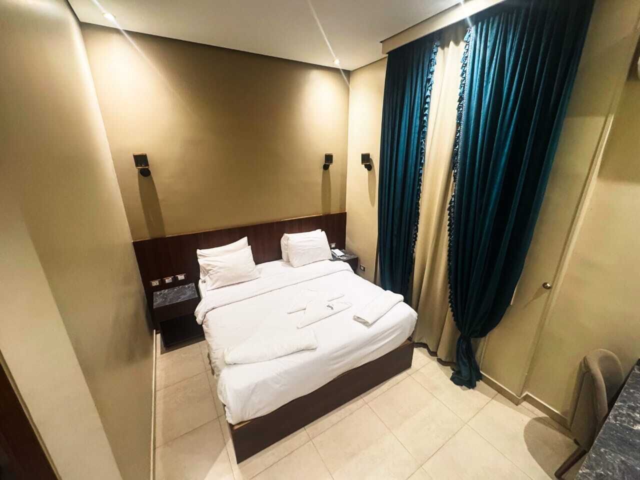 Una habitación de hotel con una cama, una mesita de noche, un escritorio y una silla.