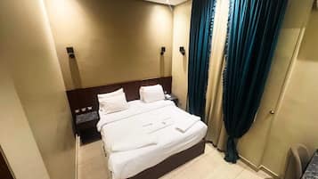 Una habitación de hotel con una cama, una mesita de noche, un escritorio y una silla.
