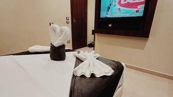 Una habitación de hotel con una cama, un televisor en la pared y una puerta.