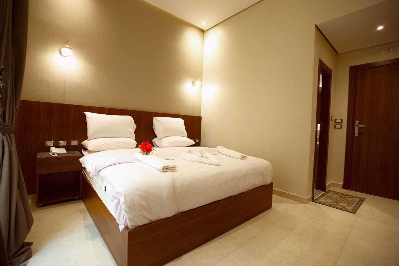 A hotel room with a large bed, bedside tables, and a wooden headboard.