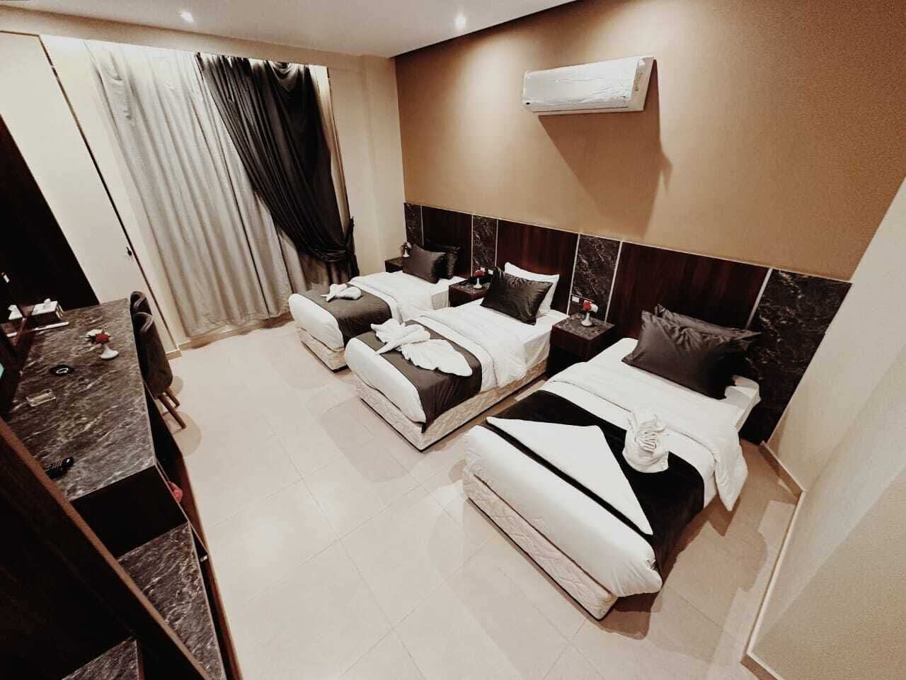 A hotel room with two beds, a desk, and a large window with curtains.