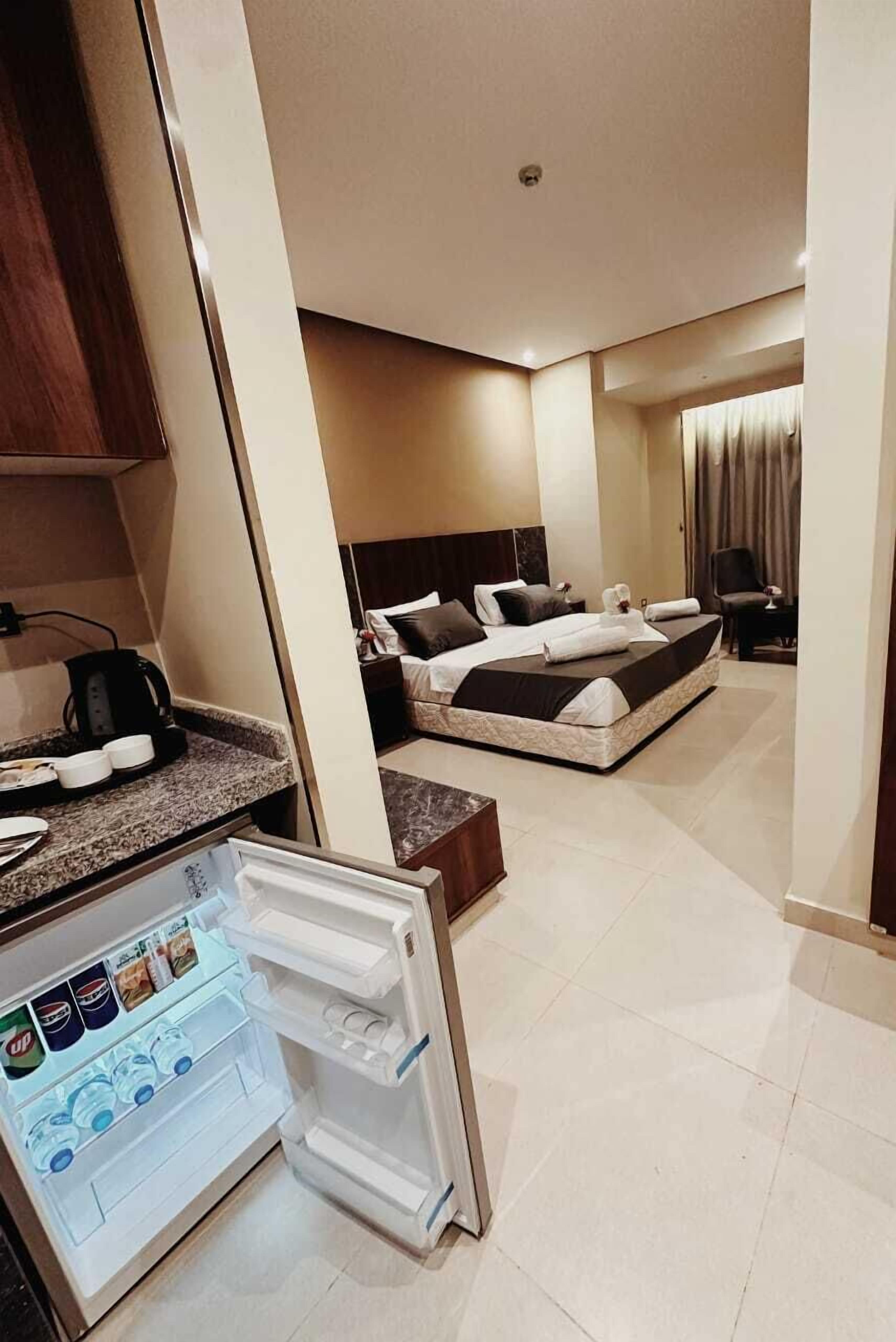 Ein Hotelzimmer mit Bett, Schreibtisch, Stuhl, Kühlschrank und Kaffeemaschine.