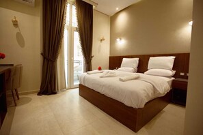 A hotel room with a large bed, a desk, and a chair. - Sama hotel (Cairo)
