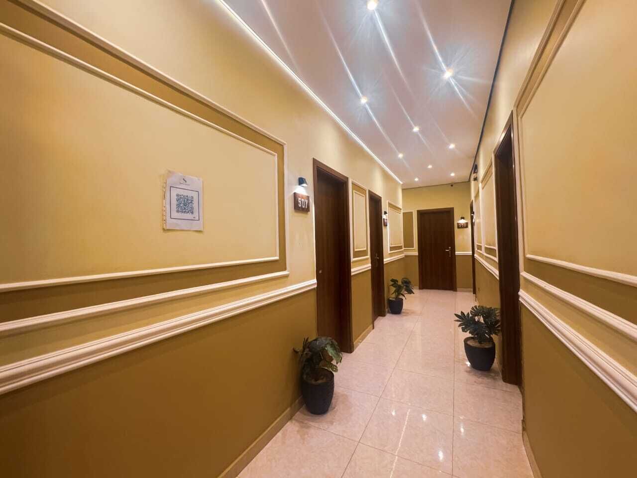 Ein Hotelgang mit cremefarbenen Wänden, einem polierten Boden und Topfpflanzen.