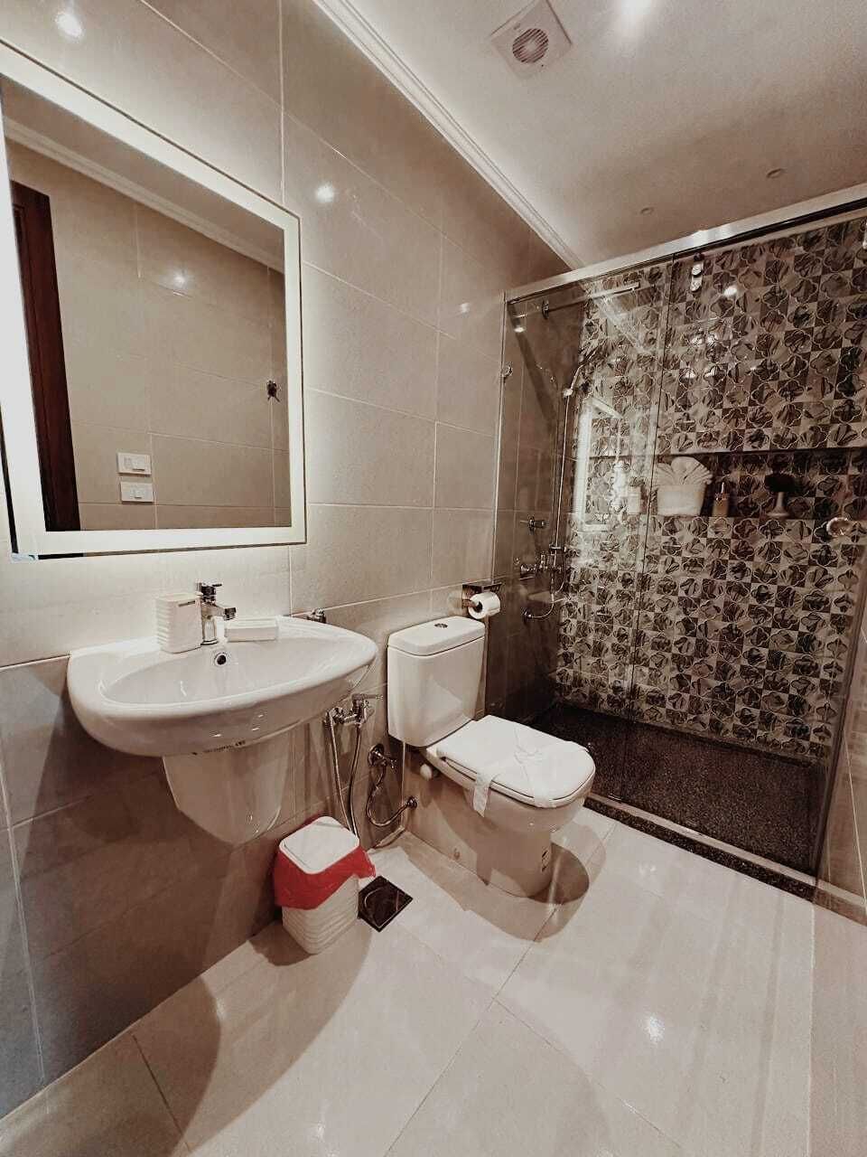 Une salle de bain moderne avec un grand miroir, un lavabo, des toilettes et un espace douche.
