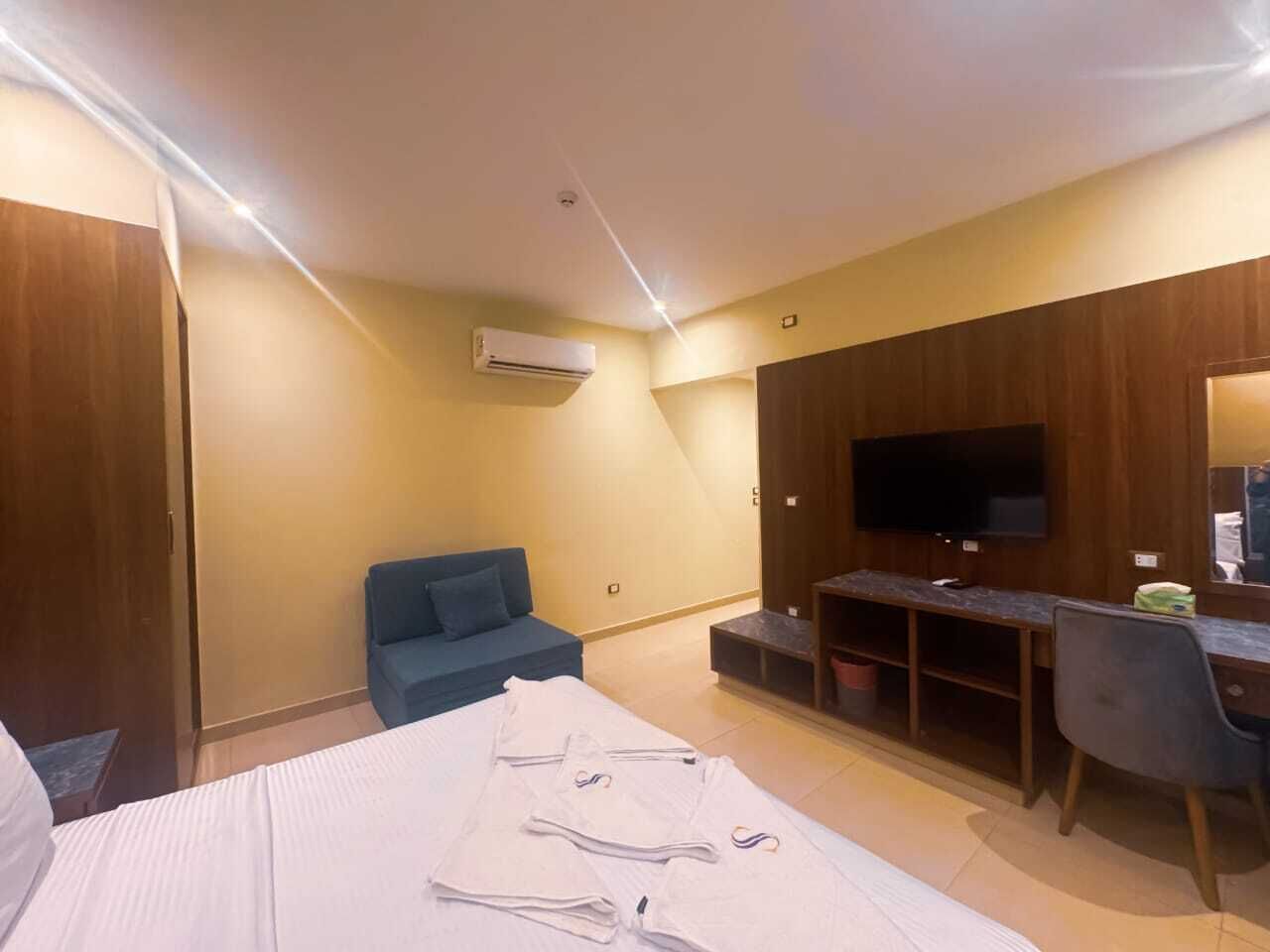 A hotel room with a bed, a desk, a TV, and a sofa.