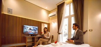 Une chambre d’hôtel avec un lit, une télévision, un bureau et une fenêtre avec des rideaux.