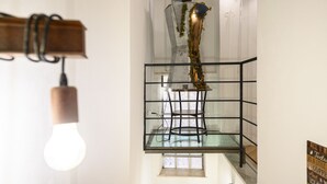 A modern staircase with a glass railing, a light fixture, and a decorative plant. - Vico Graziella 12 in Naples (Naples)