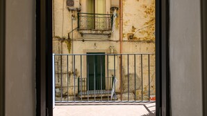 A view through a metal gate into a building with a balcony and a door. - Vico Graziella 12 in Naples (Naples)