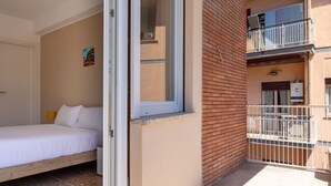 Quarto com cama, mesa de cabeceira e janela.
