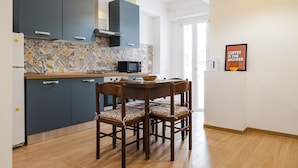 Cozinha moderna com armários azul escuro, micro-ondas e uma mesa de jantar com quatro cadeiras.