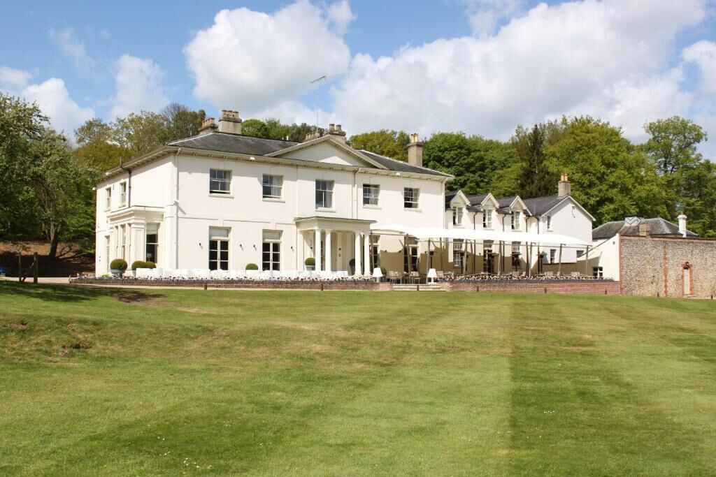 A large, white, two-story building with a symmetrical facade, a covered porch, and a well-maintained lawn in front.