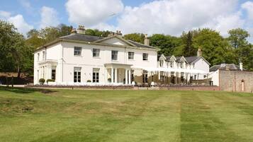 A large, white, two-story building with a symmetrical facade, a covered porch, and a well-maintained lawn in front.