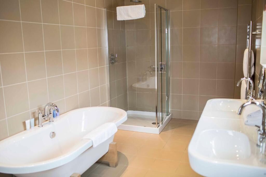 A bathroom with two sinks, a shower, and a glass-enclosed shower area.