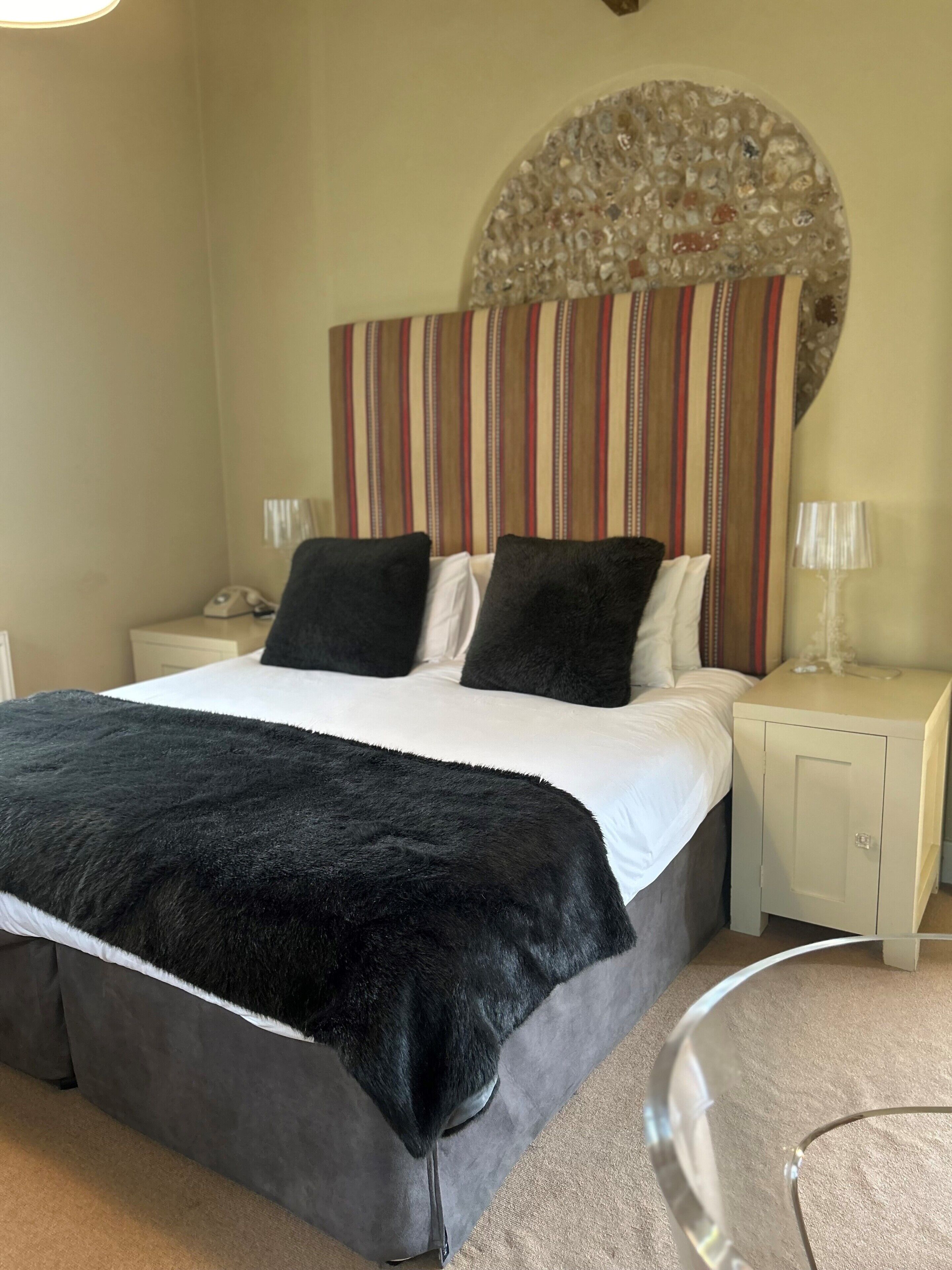 A bedroom with a bed, two nightstands, a telephone, and a decorative headboard.