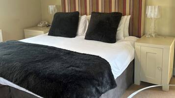 A bedroom with a bed, two nightstands, a telephone, and a decorative headboard.