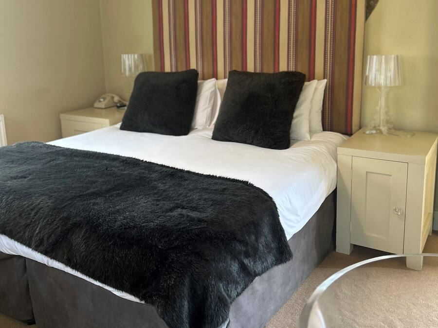 A bedroom with a bed, two nightstands, a telephone, and a decorative headboard.