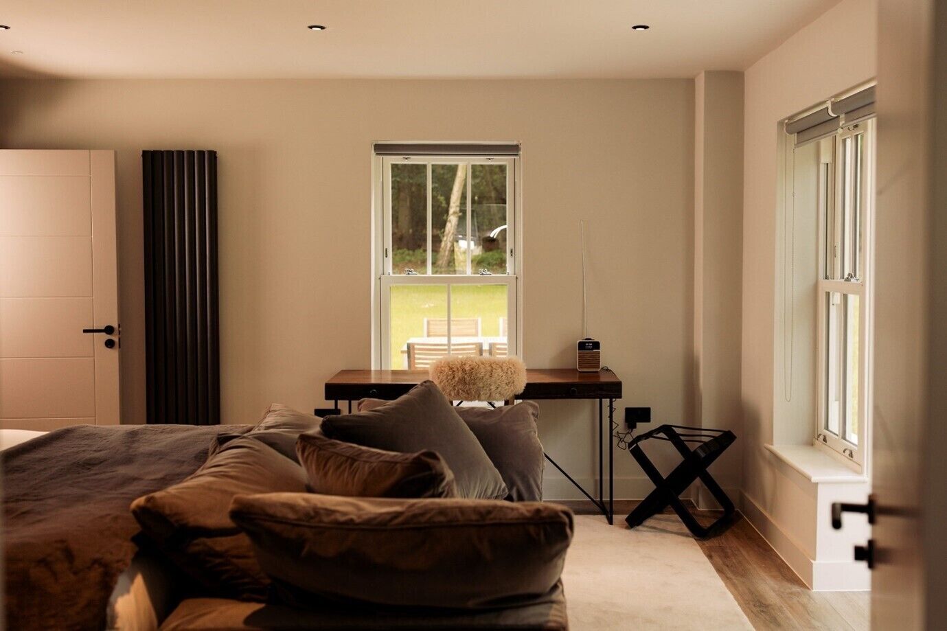 Une chambre moderne avec un grand lit, un bureau avec une chaise et une fenêtre donnant sur un paysage verdoyant.