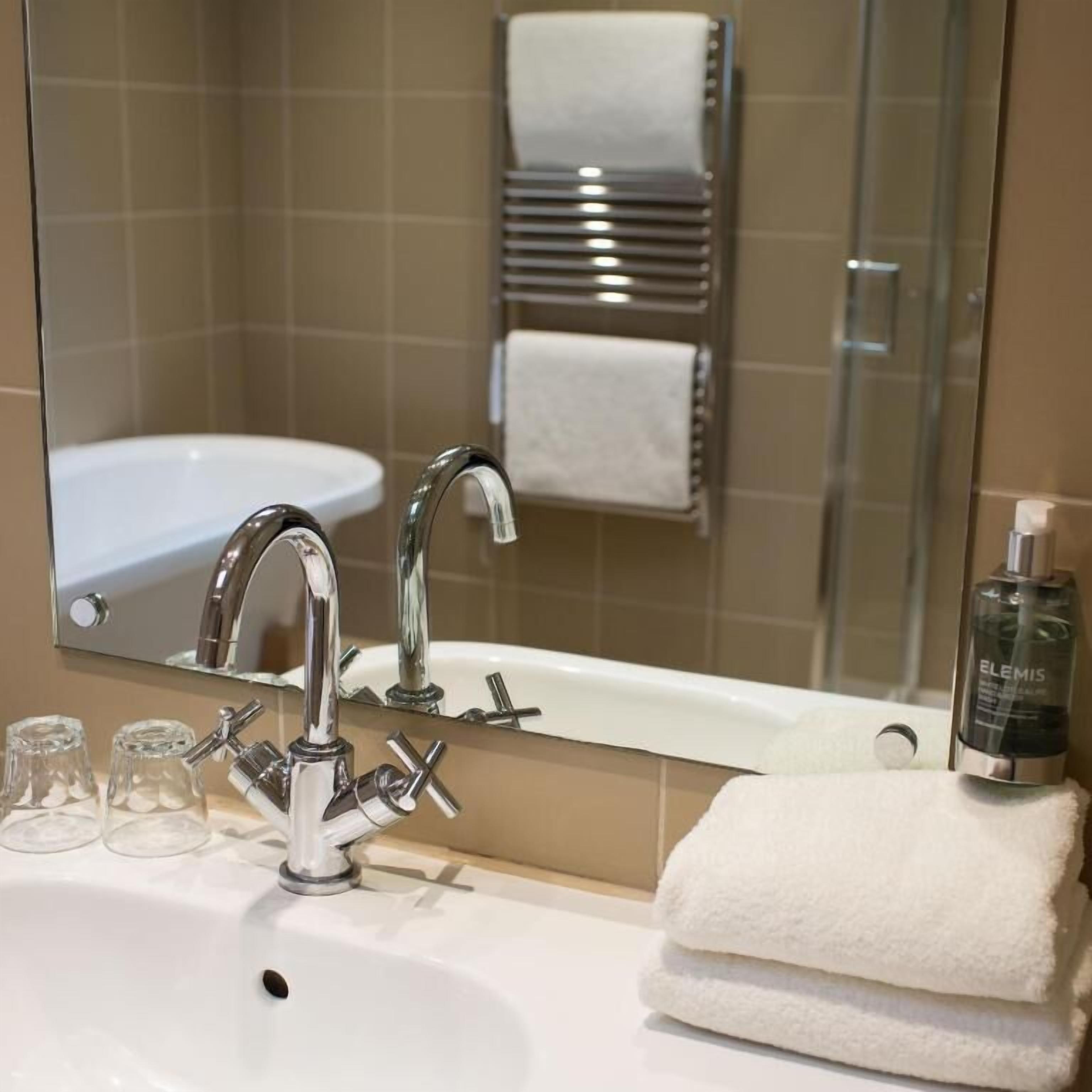 A bathroom with a sink, mirror, and towel rack.