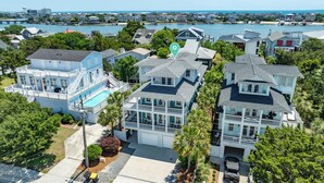 A coastal residential area with multiple two-story houses, a swimming pool, and a marina in the background. - Searenity | 5BR Marshview Retreat w/ Game Room, Elevator & Close to Beach (Wrightsville Beach)