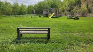 Een park met een speeltuin, een bank en picknicktafels.
