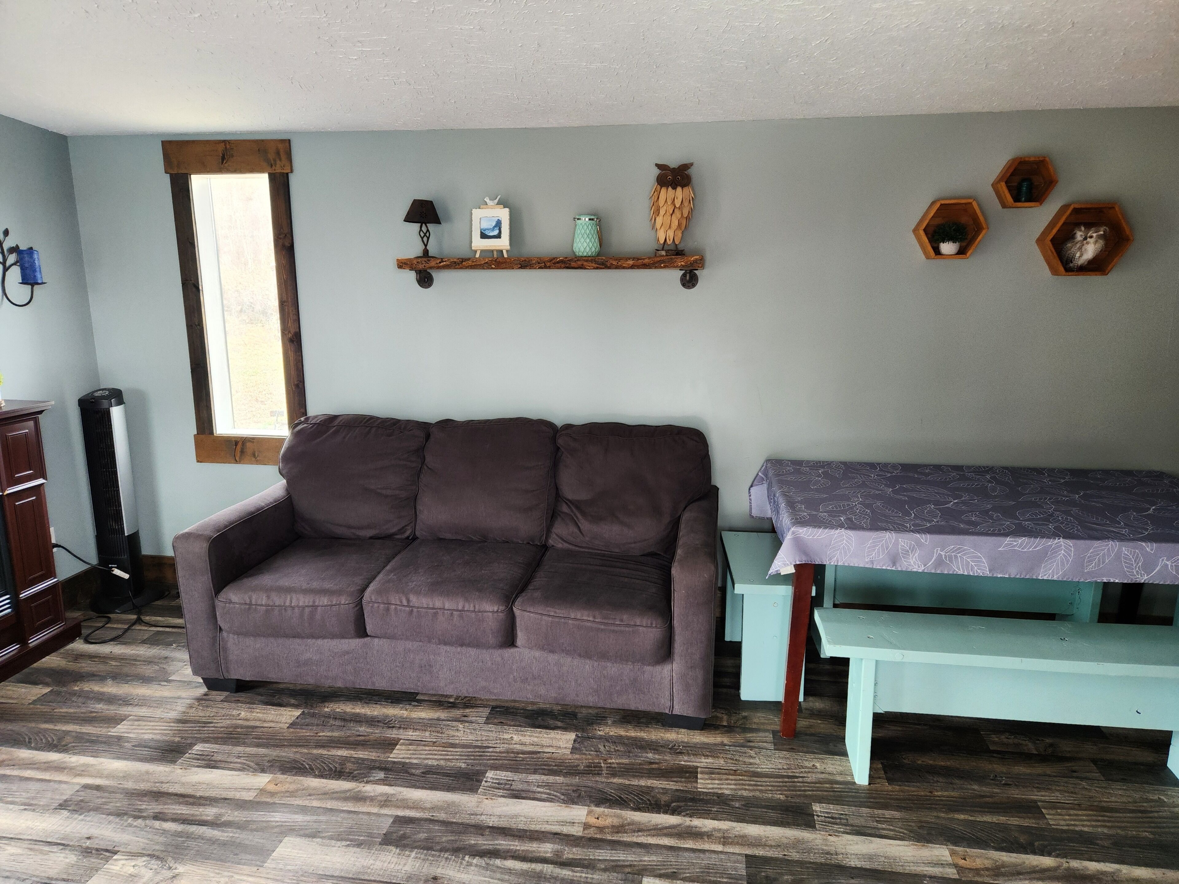 A living room with a brown sofa, a wooden table with a purple tablecloth, and a wooden bench.