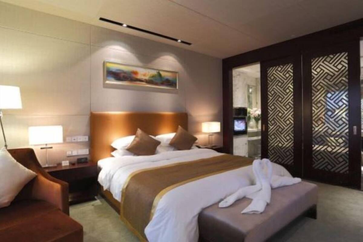 Ein Hotelzimmer mit Bett, Sessel, Schreibtisch, Fernseher und einer Wanddekoration.